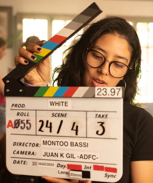 Behind-the-scenes photo of a crew member holding a clapperboard on the set of White